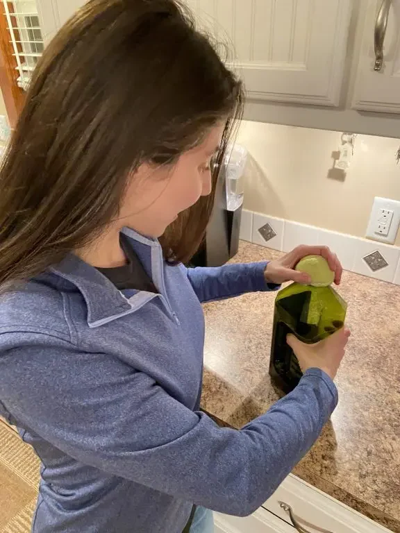 Woman using a cut tennis ball to unscrew a jar lid